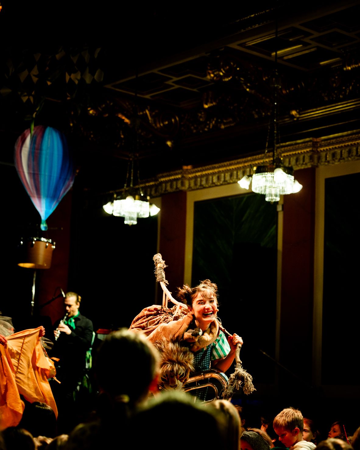 A hot-air balloon hovers above the stage in the Musikverein, the audience in the foreground.